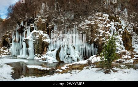 Eine Panorama-Winterszene von Rio Cuervo mit gefrorenen Wasserfällen, umgeben von schneebedeckten Bäumen und eisiger Landschaft Stockfoto