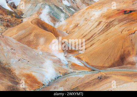 Dampf steigt aus geothermischen heißen Quellen in den farbenfrohen Rhyolithbergen in Island. Stockfoto