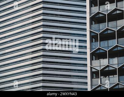 Ein Bild, das die Gegenüberstellung zweier verschiedener Wolkenkratzerfassaden zeigt, eine mit einem schlanken Streifendesign und die andere mit geometrischen Mustern Stockfoto