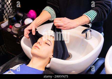 Der Kunde hat Haare in ein Handtuch gewickelt in einem Friseurbecken Stockfoto