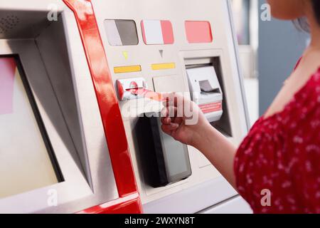 Nahaufnahme einer Frau, die einen Geldautomaten benutzt und Geld abhebt, mit Fokus auf ihre Hand und die Karte Stockfoto