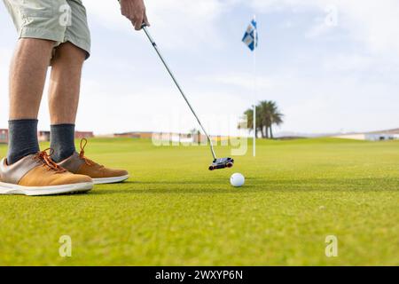 Eine zugeschnittene, nicht erkennbare Person, die während einer Golfsitzung auf einem landschaftlich reizvollen Golfplatz erfasst wurde, zeigt einen einzigartigen Stil in einem traditionellen spo Stockfoto
