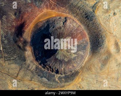 Ein Luftbild fängt die atemberaubende Weite eines vulkanischen Kraters ein und zeigt eine Vielzahl von Texturen und Farben von satten Rosten bis zu tiefen Farbtönen Stockfoto