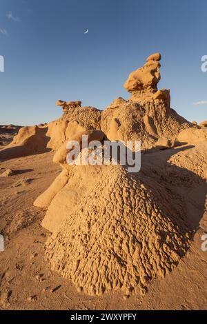 Im Goblin Valley State Park, Utah, USA, stehen unter einem Dämmerungshimmel mit einem Halbmond beeindruckende Sandsteinformationen, die als Goblins bekannt sind. Stockfoto