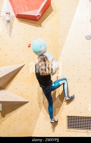 Eine Kopfaufnahme einer Klettererin, die eine Kletterwand hochklettert, um ihr Ziel zu erreichen Stockfoto