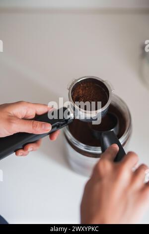 Nahaufnahme der Hände, die einen Portafilter mit frisch gemahlenem Kaffee vorbereiten Stockfoto