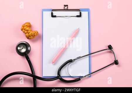 Endokrinologie. Stethoskop, Clipboard, Modell der Schilddrüse und Stift auf rosa Hintergrund, flache Lage Stockfoto