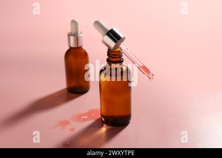 Pipette und Flaschen mit feuchtigkeitsspendendem Serum auf rosa Hintergrund Stockfoto