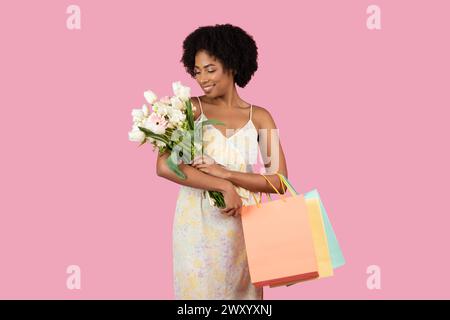 Afroamerikanerin, die Blumen mit Taschen bewundert Stockfoto