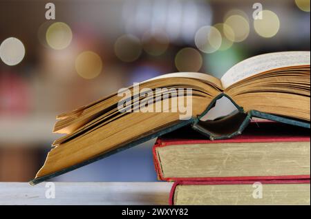 Stapel von Büchern und offenem Buch mit verschwommenem Hintergrund, Lesen, Lernen, Bildung oder Home Office Konzept Stockfoto