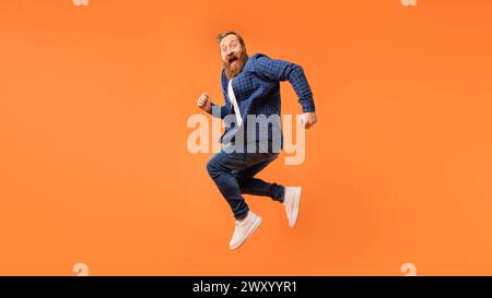 Fröhlicher Mann mit Bartsprüngen und aufgeregt schreien, Studio Stockfoto