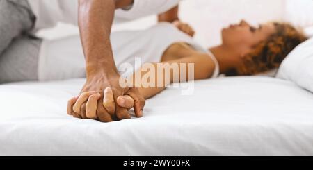 Nahaufnahme eines Paares, das Hände auf dem Bett hält Stockfoto