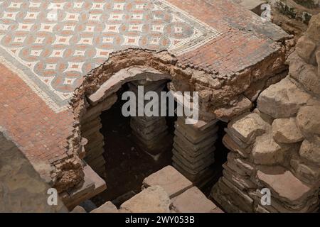 Westbadehaus in der Chedworth Roman Villa mit einem Hypokaukasus und kleinen Backsteinsäulen (Pilae), die einen Mosaikboden im Tepidarium (warmes Zimmer), Großbritannien, stützen Stockfoto