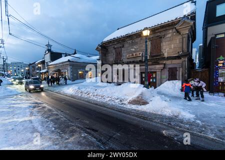 Otaru, Japan - 09. Februar 2024: Touristen und Einheimische spazieren entlang der Sakaimachi Hondori Straße, gesäumt von alten Gebäuden und traditionellen Geschäften in Hokkai Stockfoto