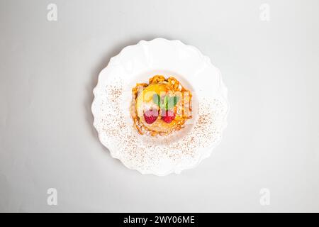 Flauschige Pfannkuchen mit Himbeeren und Minzblättern auf einer weißen Platte vor einem sauberen weißen Hintergrund. Nahaufnahme. Stockfoto