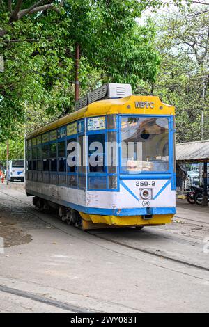 Am 19. März 2024 wartet eine Straßenbahn mit einem Reisebus auf ihre nächste Fahrt im Depot Esplanade in Kalkutta, Westbengalen, Indien. Stockfoto