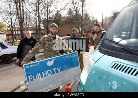 KIEW REGION, UKRAINE - 02. APRIL 2024 - Soldaten tragen Fernsehgeräte, die ihnen von der Stiftung Safe Region Charitable anlässlich der Veranstaltung anlässlich des zweiten Jahrestages der Befreiung der Region Kiew von den russischen Besatzern, Vyshneve, Kiew Region, Nord-Ukraine, präsentiert wurden. Stockfoto