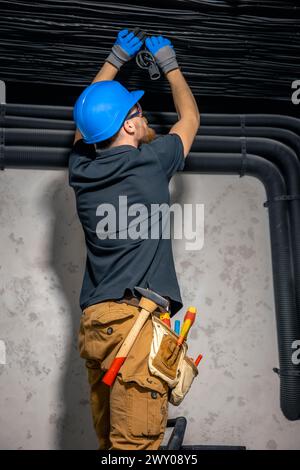 Elektriker, der elektrische Kabel an der Decke im Haus verlegt. Stockfoto