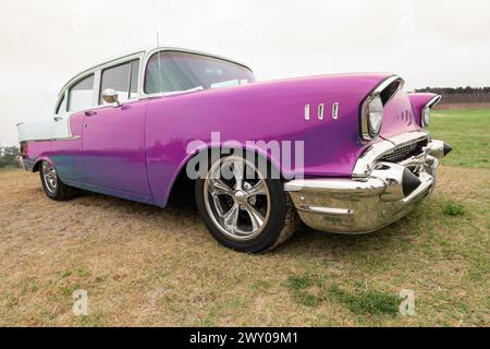 Seitenansicht eines amerikanischen Oldtimers aus den 50er Jahren. Niedriger Winkel mit rosafarbenem und verchromtem Kotflügel und Grill. Stockfoto