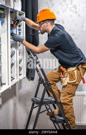 Ein Elektriker arbeitet in einer Schalttafel mit einem elektrischen Anschlusskabel. Stockfoto