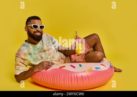 Ein Mann in entspannter Haltung sitzt auf dem pulsierenden rosa Donut-Schwimmer und strahlt ein Gefühl von Ruhe und Freizeit auf dem Wasser aus. Stockfoto