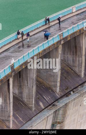 KUROBE-STAUDAMM, JAPAN - 26. MAI 2023: Touristen trotzen stürmischem Himmel und Regen auf dem Kurobe-Staudamm, Japans höchstem Staudamm. Stockfoto