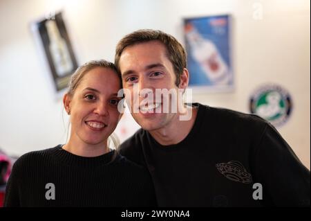 Porträt eines lächelnden und glücklichen Hochzeitspaares in einer Cocktailbar. Sie lächeln beide, sie sind schwarz gekleidet. Im Hintergrund gibt es Bokeh Stockfoto