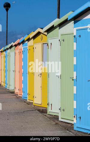 Strandhütten in seaford East Sussex UK mehrfarbige Reihe von Hütten am Strand in wechselnden Pastellfarben in der Frühlingssaison an einem kalten windigen Tag Stockfoto