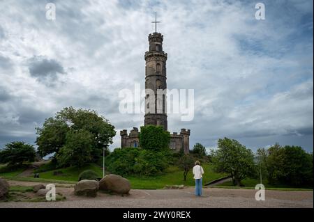 Eine Frau, die auf das Nelson Monument in Calton Hill, Edinburgh, Schottland, Großbritannien starrt Stockfoto