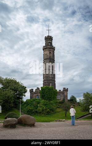 Eine Frau, die auf das Nelson Monument in Calton Hill, Edinburgh, Schottland, Großbritannien starrt Stockfoto