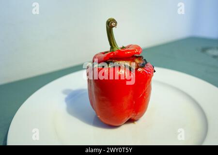 Rote Paprika gefüllt mit Gemüse auf einem weißen Teller. Stockfoto