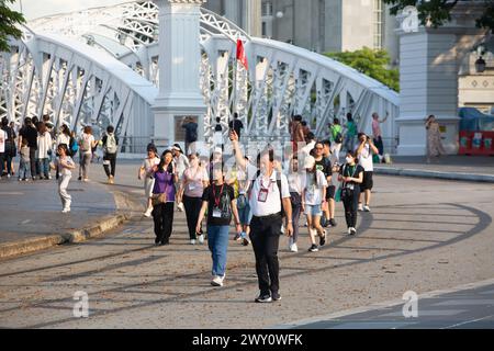Ein männlicher chinesischer lizenzierter Reiseleiter hält eine Stangenfahne, um sicherzustellen, dass seine Gruppe ihm in der Mitte der Straße zum nächsten Ziel folgt. Singapur. Stockfoto