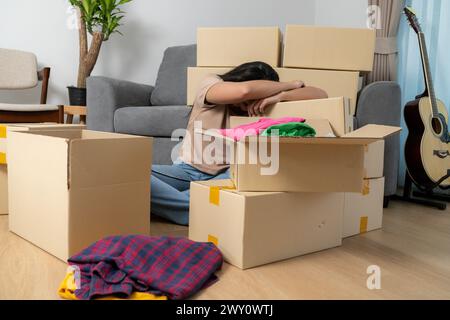 Die junge Frau ist müde vom Umziehen und Verpacken ihrer Sachen, während sie in ein neues Haus zieht Stockfoto