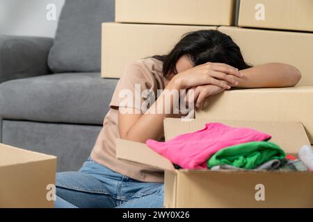 Die junge Frau ist müde vom Umziehen und Verpacken ihrer Sachen, während sie in ein neues Haus zieht Stockfoto