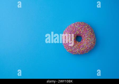 Ein rosafarbener Donut auf pastellblauem Hintergrund Stockfoto