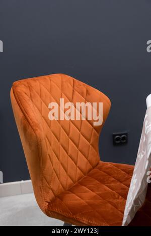 Weißer Holztisch kombiniert mit orangefarbenen Stühlen mit weichen Stoffpolstern. Es gibt eine weiße Lieferung mit einem mehrfarbigen Blumenstrauß auf dem t Stockfoto
