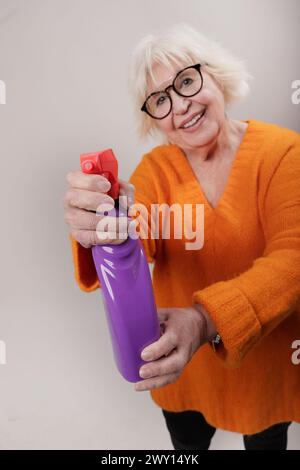 Schöne Seniorin mit sauberem Produkt in den Händen im Studio Stockfoto