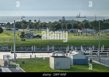 Port Canaveral, Florida, USA - 30. Juli 2023: Grüner Parkplatz und Picknickplatz mit Fischereischiff am Horizont Stockfoto