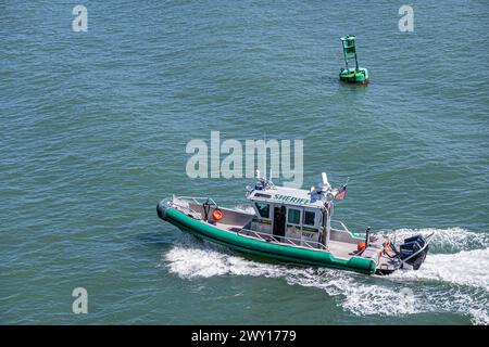 Port Canaveral, Florida, USA - 30. Juli 2023: Sheriff-Schnellboot-Nahaufnahme, während es ein Kreuzfahrtschiff auf grünlichem Atlantikwasser eskortiert Stockfoto