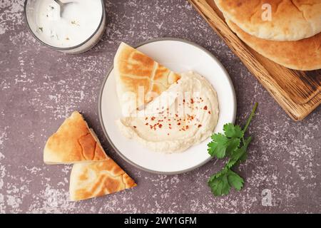 Teller mit leckerem Fladenbrot mit Hummus auf grauem Hintergrund Stockfoto