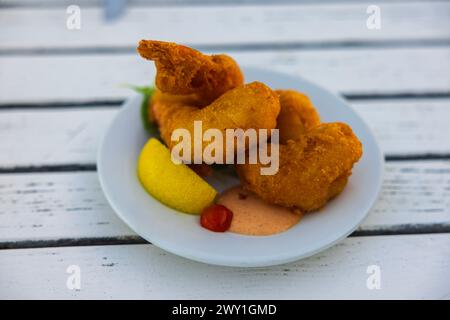 Nahaufnahme von gebackenen Garnelen im Teig, die auf einem Teller auf einem Restauranttisch serviert werden. Stockfoto
