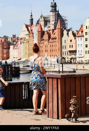 Familientouristen, die an einer kleinen Metallskulptur Hewelion der Löwe in der Altstadt von Danzig, Polen, Europa, EU vorbeifahren Stockfoto