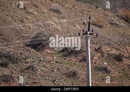 Alte Stromleitung mit geringem Stromfluss bei niedriger Haushaltsspannung auf dem Land. Elektrische Übertragung, Betonsäule, Strom transportieren Stockfoto