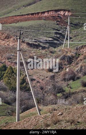 Alte Stromleitung mit geringem Stromfluss bei niedriger Haushaltsspannung auf dem Land. Elektrische Übertragung, zwei Betonpfeiler, die Elektronen tragen Stockfoto