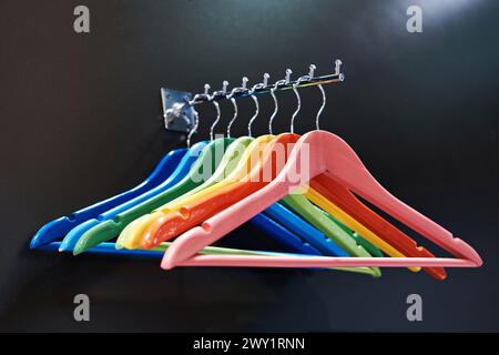 Bunte Kleiderbügel an Kleiderstange im Laden Stockfoto