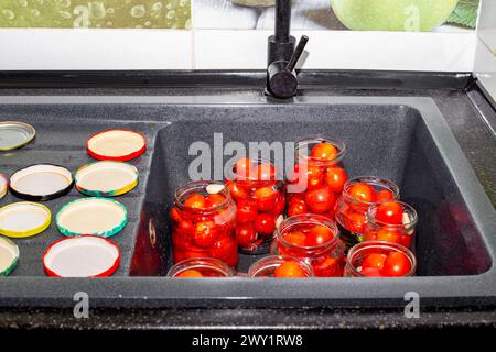 Rote reife Tomaten werden in Gläser zum Einlegen und Konservieren gelegt. Konservierung und Verarbeitung von Gemüsepflanzen. Stockfoto