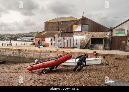 Drei Männer ziehen das Schlauchboot am Teign Beach in Teignmouth, Devon, Großbritannien. Stockfoto