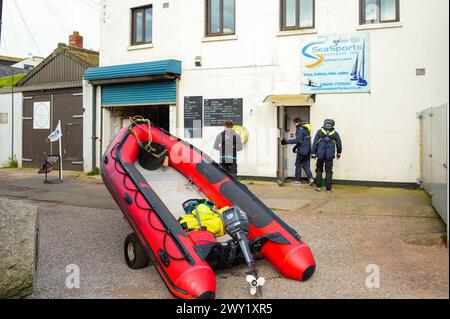 Drei Männer, nachdem sie ein Schlauchboot auf einem Wohnwagen am Teign Beach in Teignmouth, Devon, gezogen haben, kommen an ihrem Ziel an. Stockfoto