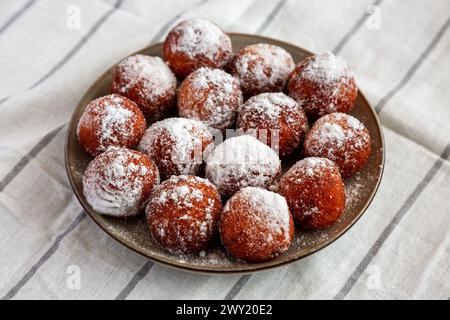 Hausgemachte gebratene Donut Holes mit Puderzucker auf einem Teller, Seitenansicht. Stockfoto