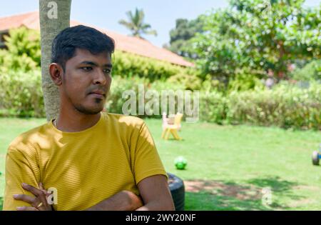 Ein Indianer sitzt nachdenklich auf einer Bank in einem friedlichen Garten, in warmes Sonnenlicht getaucht. Stockfoto